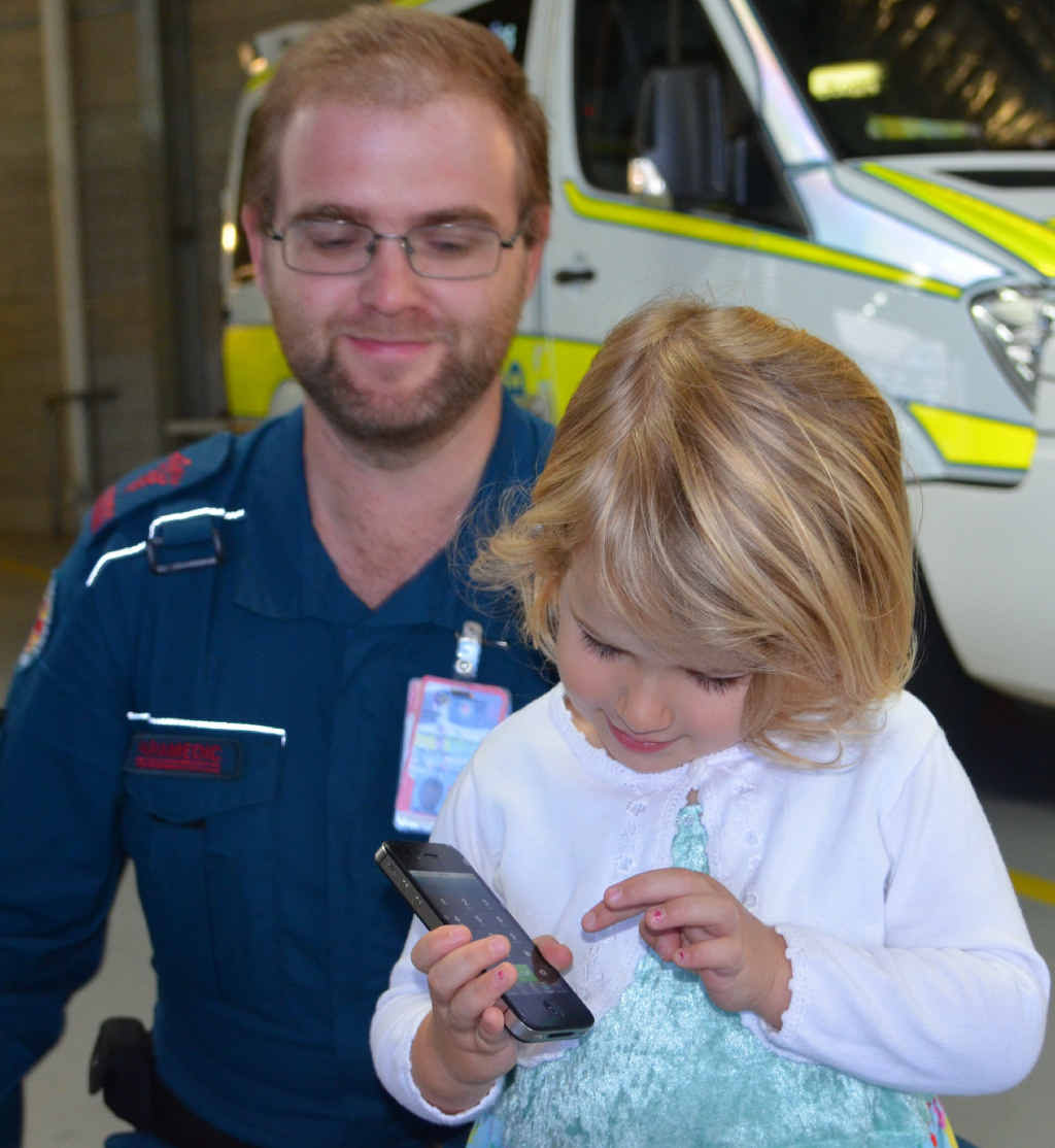 Paramedic Andrew Murray shows three-year-old Cadence Manfield how to dial 000.